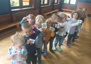Dzieci z grupy 2 stoją jedno za drugim pokazując otrzymane pamiątkowe naklejki
